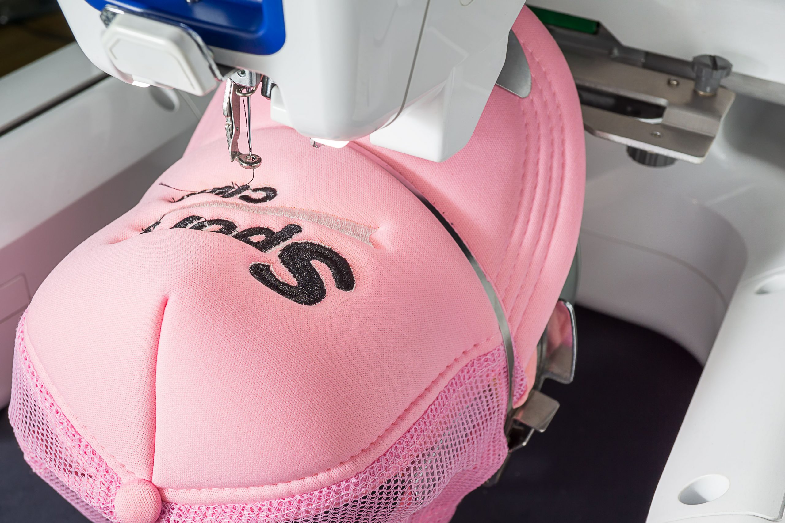 stock-photo-close-up-image-of-white-embroidery-machine-and-emboridered-pink-sport-cap-on-the-hoop-1339606385