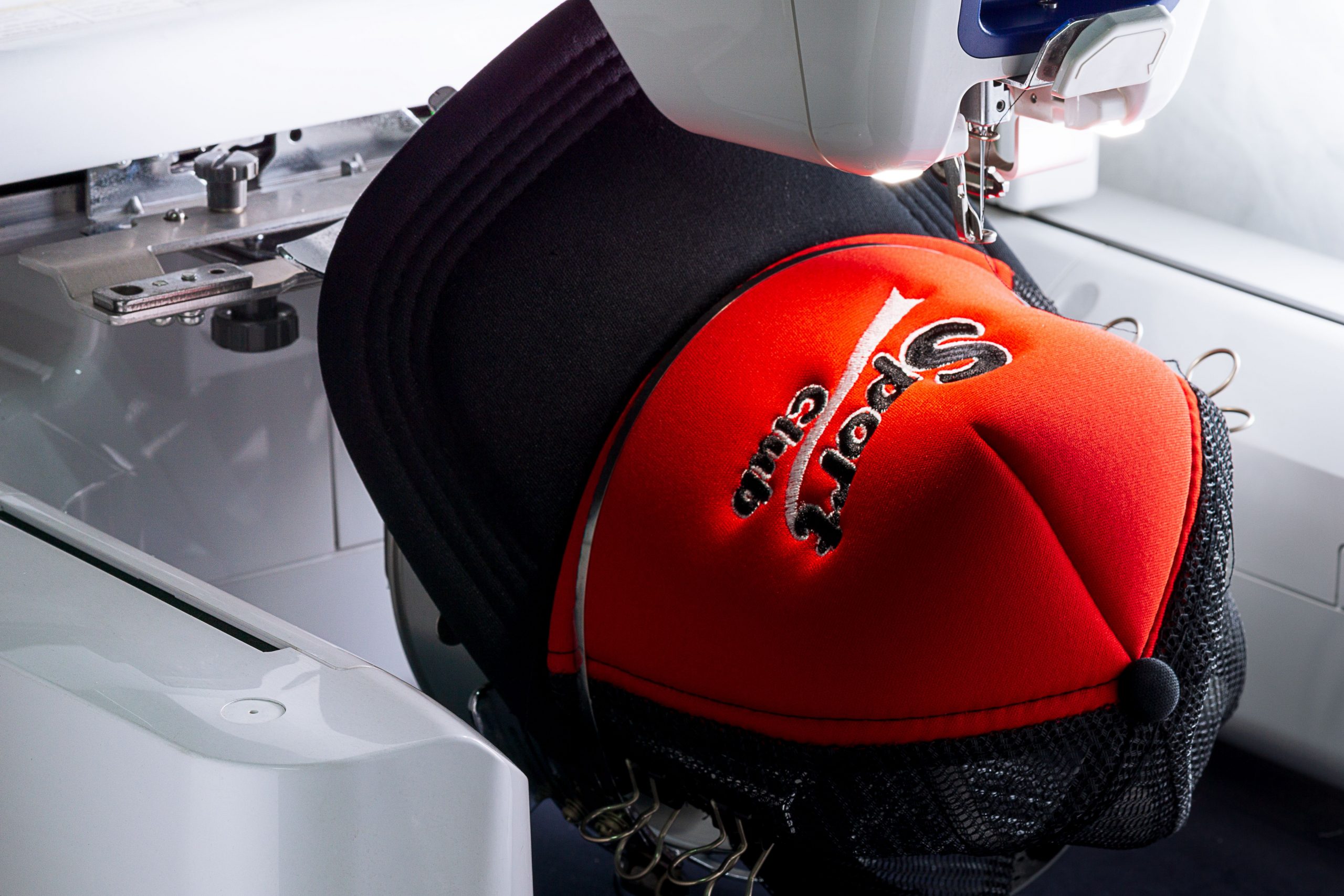 stock-photo-close-up-picture-of-sport-cap-red-and-black-color-on-the-hoop-of-embroidery-machine-1358289974